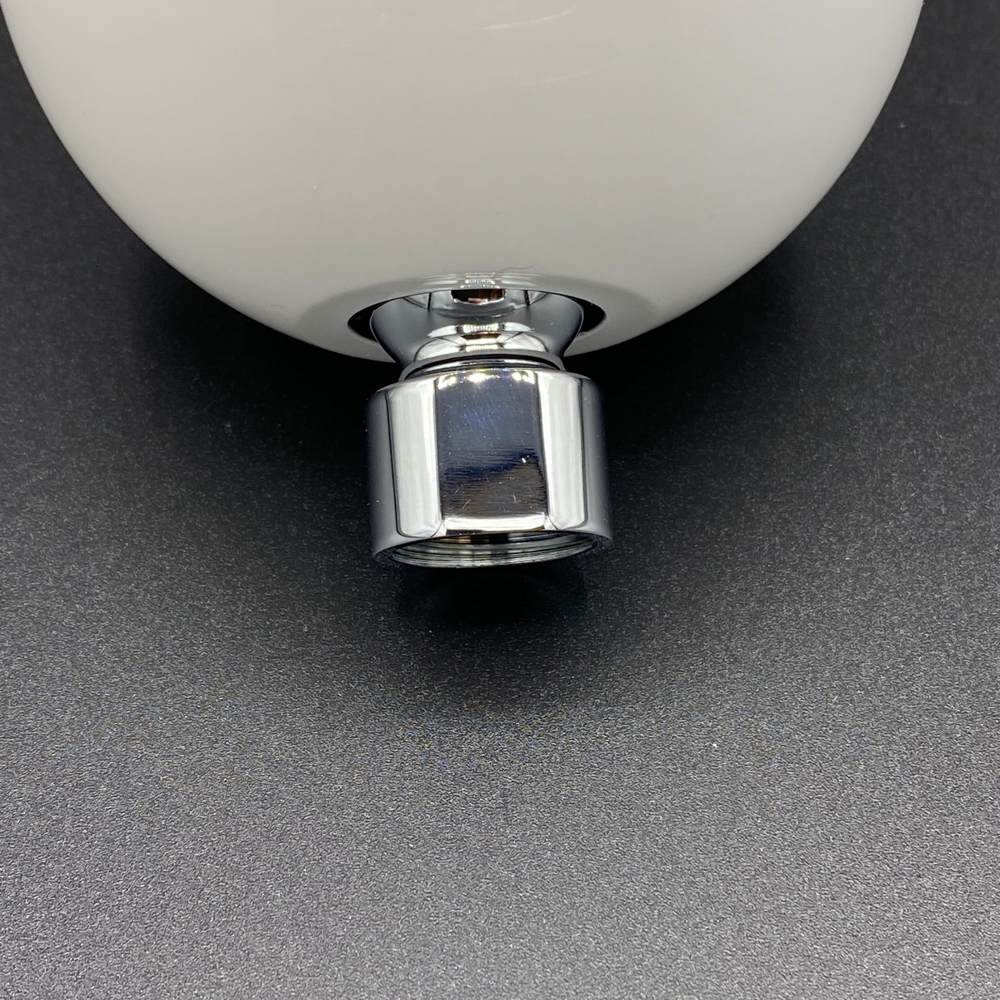 Close-up of shower head wall attachment with a metallic base on a dark gray background