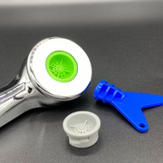 Tubing connector with green light, white cap, and blue tool on a gray background