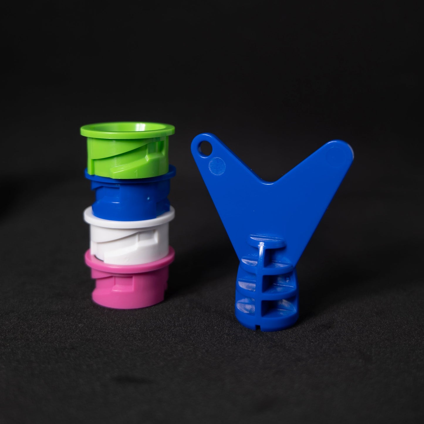 Stack of colorful replacement inserts with a blue tool on a black background